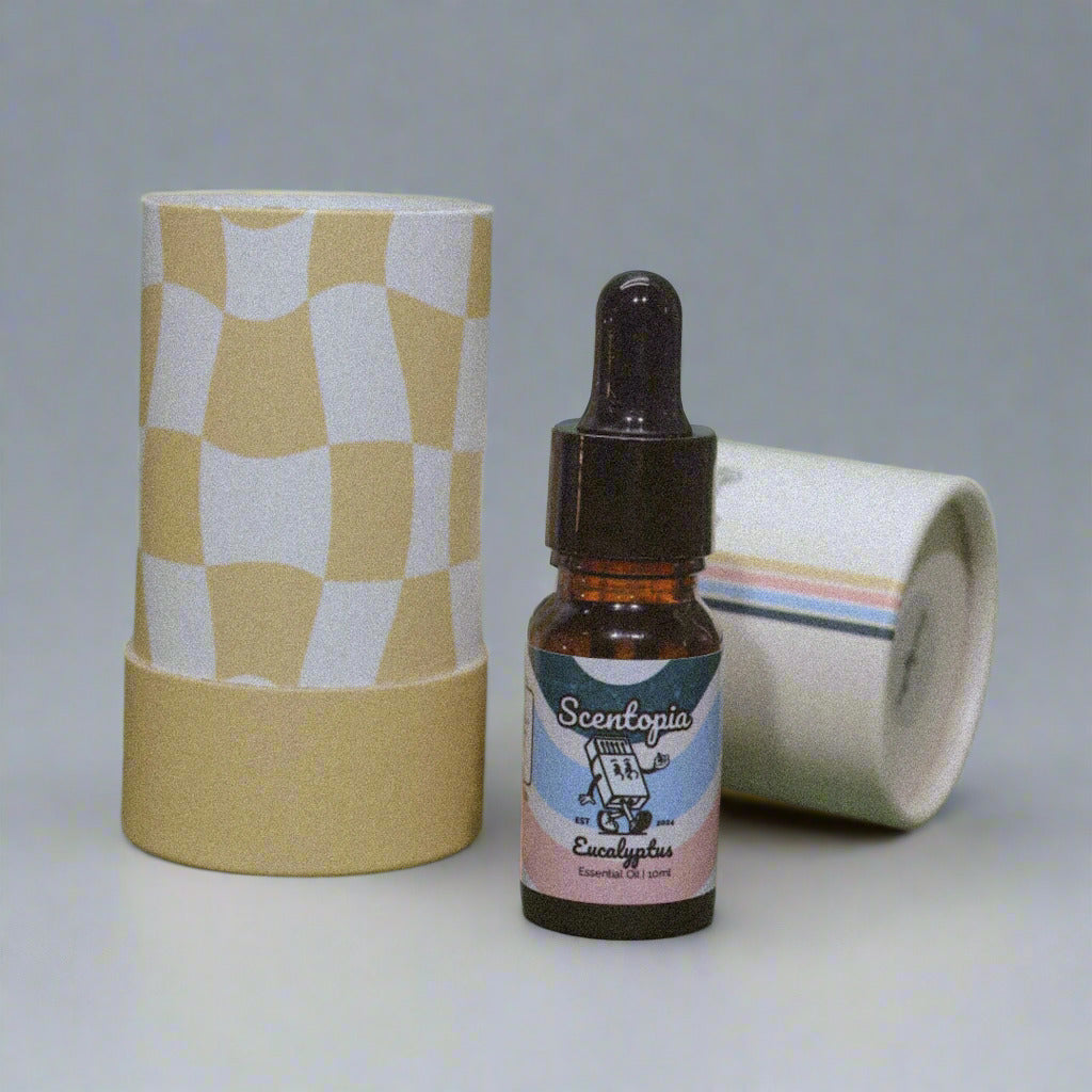 A bottle of Scentopia Eucalyptus Essential Oil with a dropper, placed next to a beige and white checkered box on a green background.