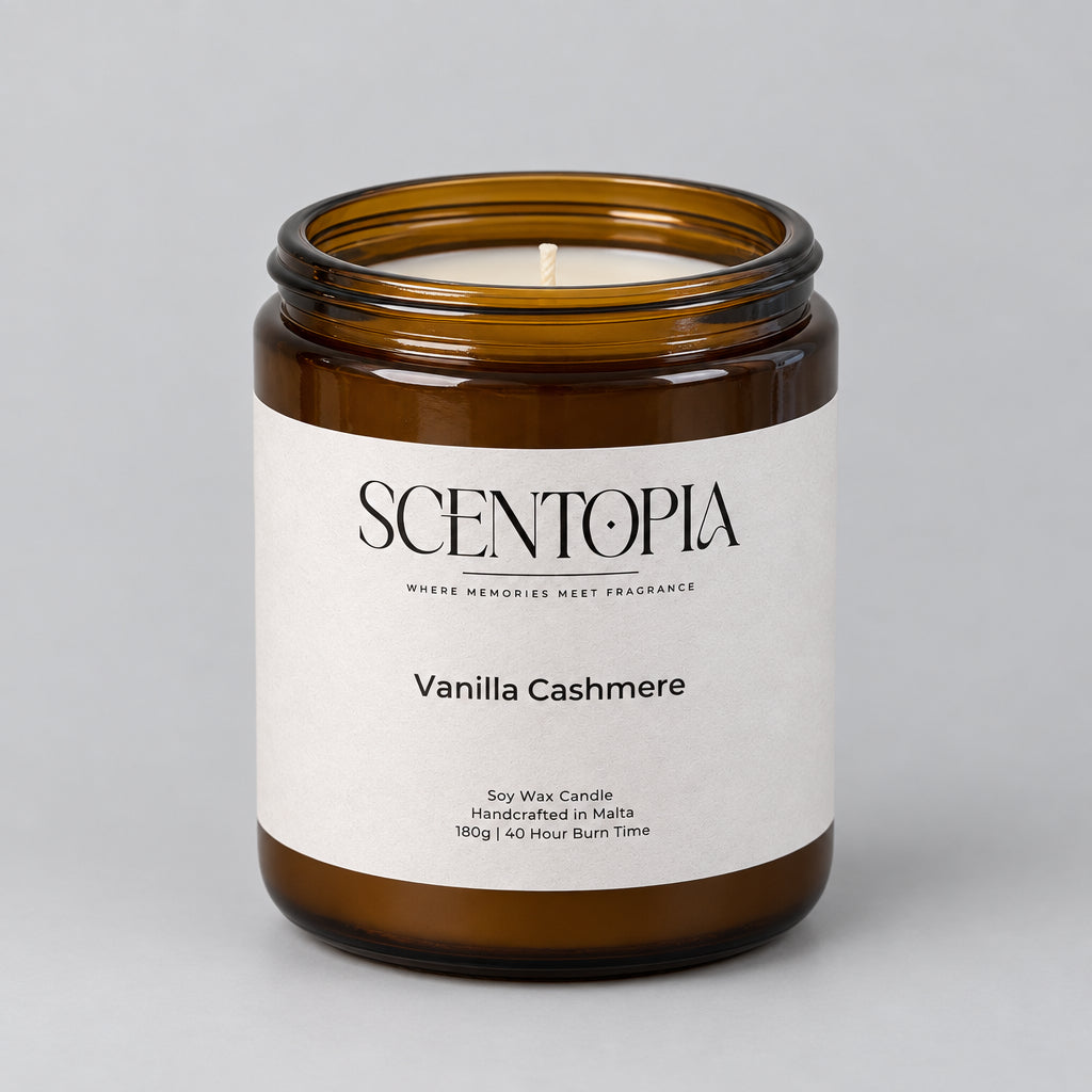 A Scentopia Vanilla Cashmere soy wax candle in an amber glass jar, set on a wooden surface against a plain light background.