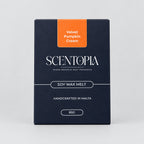 A box of Scentopia Velvet Pumpkin Cream soy wax melt placed on a wooden surface, with two pale cream wax bars partially visible at the left and right edges.
