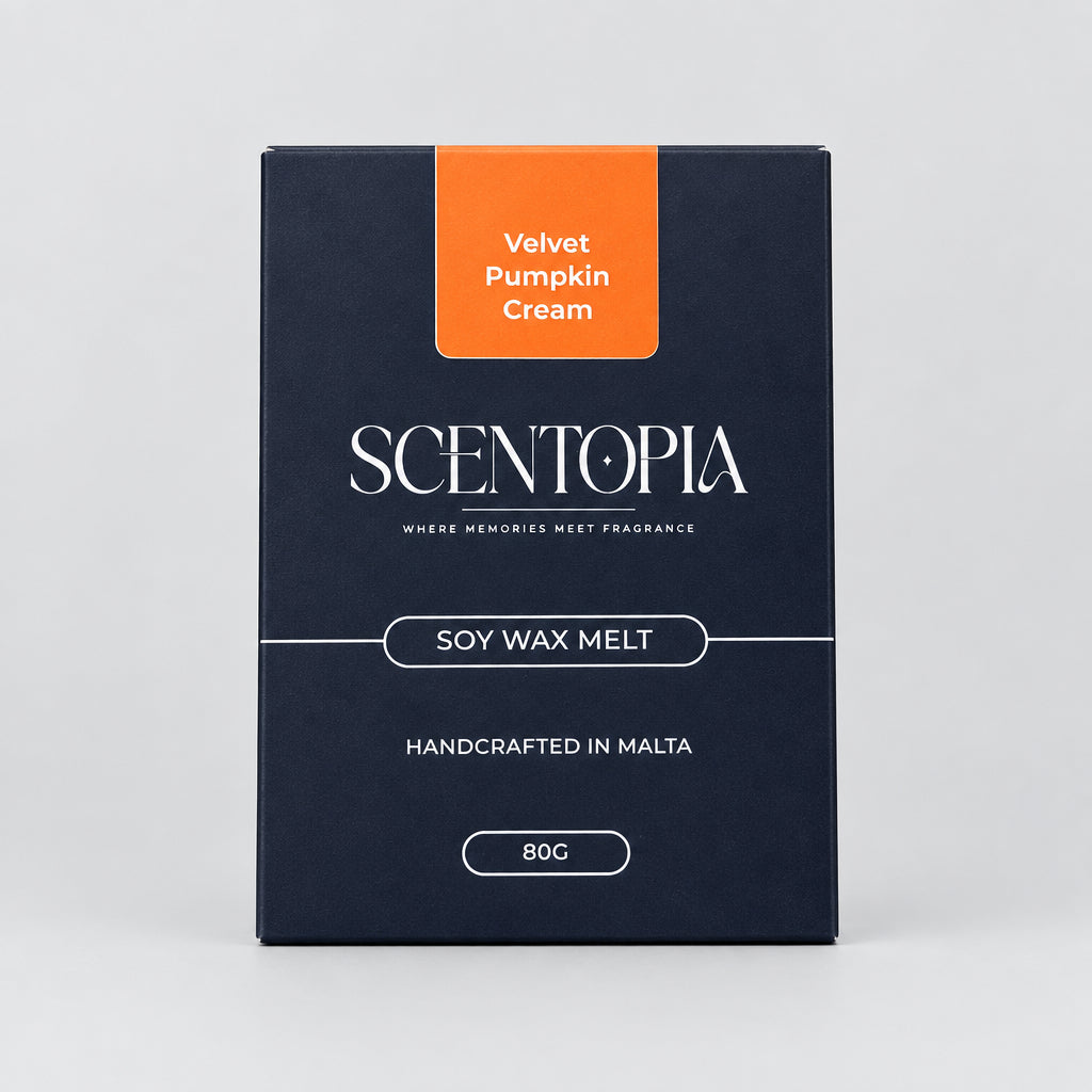 A box of Scentopia Velvet Pumpkin Cream soy wax melt placed on a wooden surface, with two pale cream wax bars partially visible at the left and right edges.