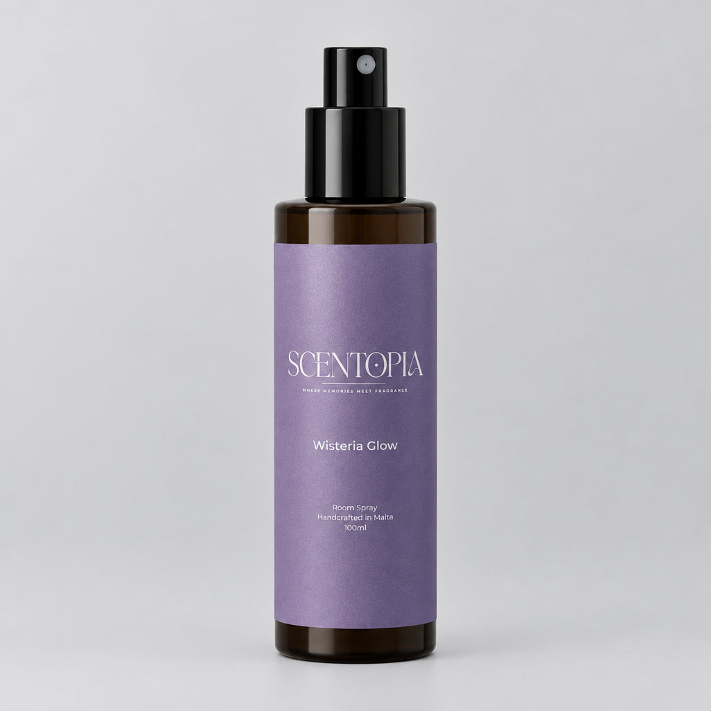 A bottle of Scentopia Wisteria Glow room spray with a lavender purple label and black spray nozzle, resting on a wooden surface against a plain light beige wall.